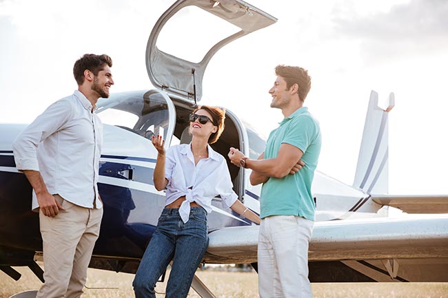 Happy friends standing and talking near small plane