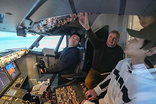 Students learn from an instructor inside a flight simulator